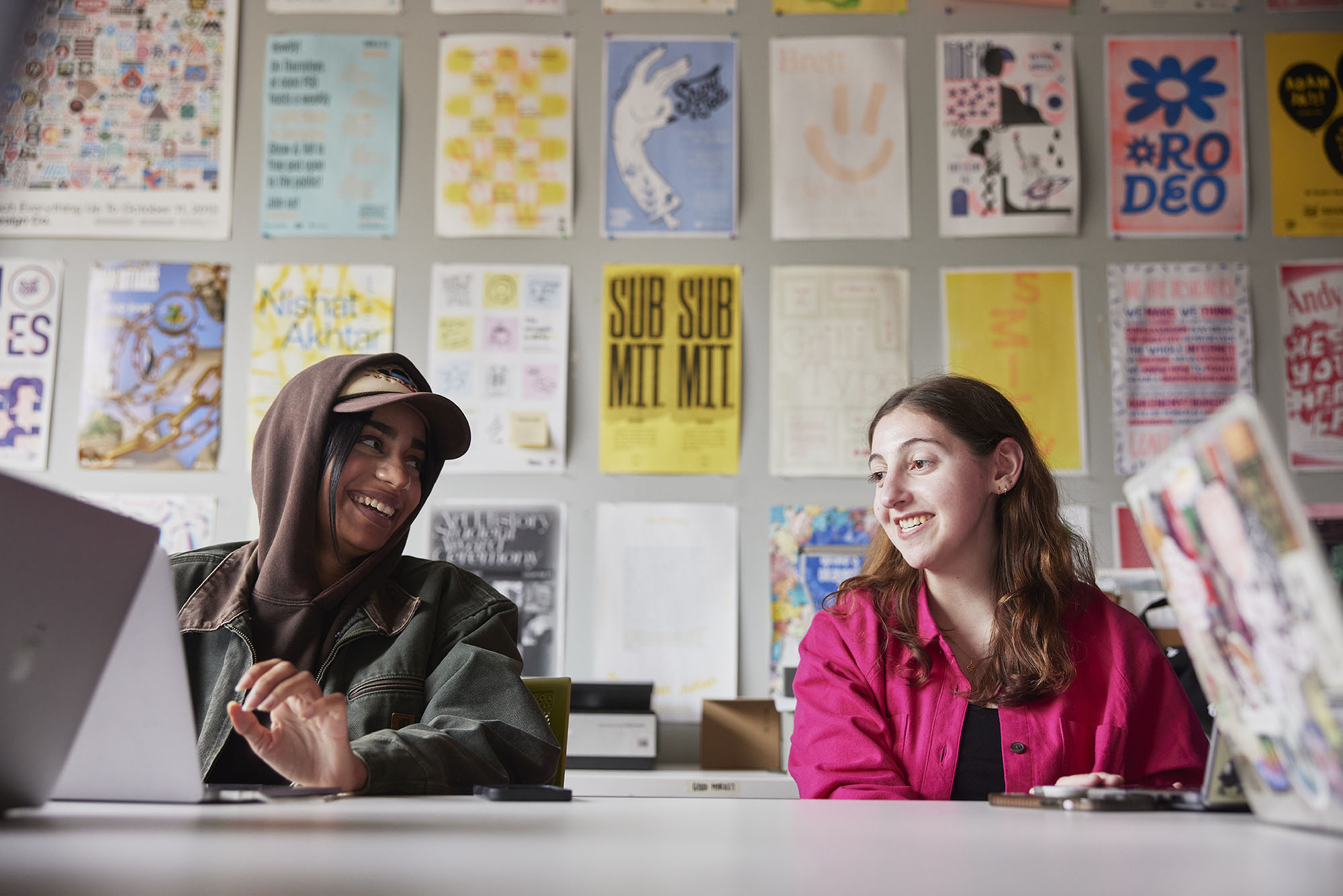 Graphic Design students laughing together while sitting at a studio table